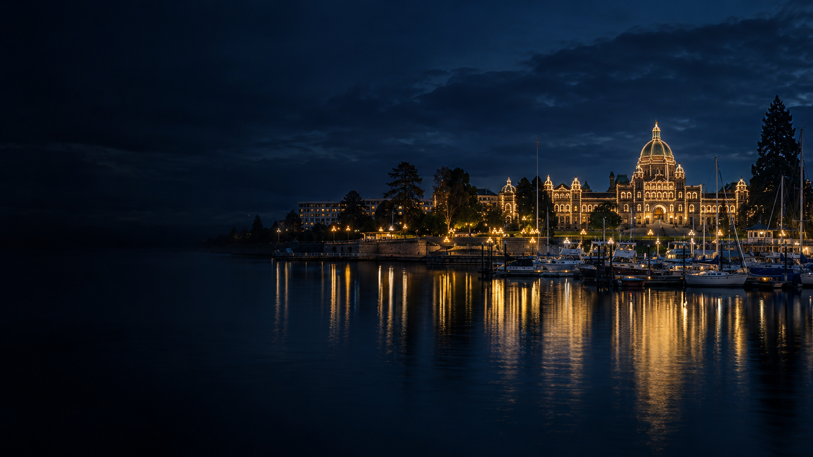 Victoria’s Inner Harbour at blue hour, with the illuminated Parliament Buildings and boats reflected in the water
